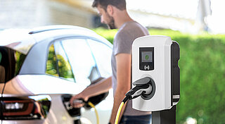 Firmenwagen zuhause laden Abrechnung, Mann lädt Elektro Dienstwagen zuhause.