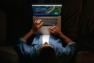 Mann am Laptop besucht Website und Onlineshop oder Online Kundenportale 