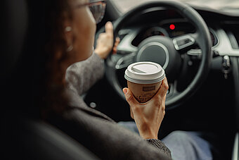 Tankstelle Shop. Frau sitzt mit Alvore Kaffee im Auto